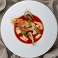 French bouillabaisse fish soup with shrimp, mussels and scallop. In a white plate on a textile background. Top view Royalty Free Stock Photo