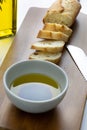 A french bread baguette sliced up on a cutting board with a bowl of olive oil with a splash of balsamic vinegar along side a bott Royalty Free Stock Photo