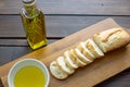 A french bread baguette sliced up on a cutting board with a bowl of olive oil with a splash of balsamic vinegar along side a bott Royalty Free Stock Photo