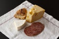 French brie and Swiss Emmental cheese with slices of salami sausage and a home baked bun placed on a white napkin background Royalty Free Stock Photo