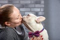 French bulldog on the hands of his master. It is felt that the girl loves her pet and hugs and kiss him tightly.