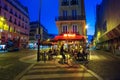 French cafe with tables outdoor in Paris and blurred moving woman on bicycle. Amazing Blue hour