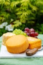 French cheeses collection, yellow Riche de Saveurs and Le peche des bons peres cheeses served on white marble plate outdoor in Royalty Free Stock Photo