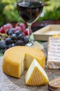 French cheeses collection, yellow Riche de Saveurs, Vieux Pane and Le peche des bons peres cheeses served with glass of red port Royalty Free Stock Photo