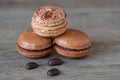 French Chocolate & Coffee Macaroons And Coffee Beans, Tasty Gormet Meringue Cookie Sandwich Cake on Vintage Wood Background