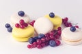 French Colorful Macarons White and Yellow Macarons on Blue Background with Fresh Red Currant Copy Space Horizontal French Dessert