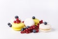 French Colorful Macarons White and Yellow Macarons on White Background with Fresh Red Currant and Blueberry Horizontal Dessert
