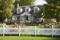 french country house exterior with beautifully manicured lawn, blooming flowers and white picket fence Royalty Free Stock Photo