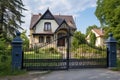 french country house with a steep hipped roof and an ornate iron gate