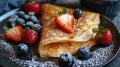 French crepes with fresh strawberries, blueberries, and powdered sugar on a dark plate