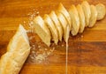 French crisp fresh baguette with a golden crust or a long loaf baked in a bakery and cut into slices on a wooden board