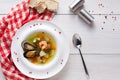 French seafood soup with white fish, shrimps and mussels in plate at wooden background