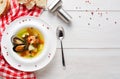 French seafood soup with white fish, shrimps and mussels in plate at wooden background
