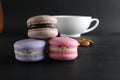 French dessert cuisine three macaroons lie pyramid next to lies almonds and a cup of tea coffee in the background on a black Royalty Free Stock Photo