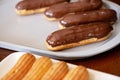 French dessert eclairs or profiteroles with dark chocolate glaze. Pastry cakes with cream and topping. Soft selective focus Royalty Free Stock Photo