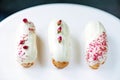 French dessert eclairs or profiteroles with rose-flavored white chocolate glaze, on a white background. Pastry cakes with custard Royalty Free Stock Photo