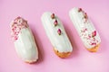 French dessert eclairs or profiteroles with rose-flavored white chocolate glaze, on a pink background. Pastry cakes with custard, Royalty Free Stock Photo