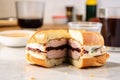 a french dip sandwich sliced open revealing layers, on grainy countertop