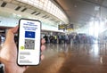 French EU Digital COVID Certificate with the QR code on the screen of a mobile held by a hand with blurred airport in the