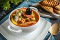 French fish soup Bouillabaisse with seafood, salmon fillet, shrimp, rich flavor, delicious dinner in a white beautiful plate. Royalty Free Stock Photo