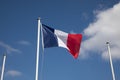 French flag at the top of a mast floats in the wind with two other empty masts for mockup country flags on sky Royalty Free Stock Photo