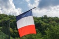 French flag waving in wind on green forest hill and sky with clouds background Royalty Free Stock Photo