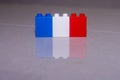 French flag white, red and blue made of toy blocks on a tile with a reflection and space to add concept.