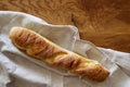 French fresh crispy baguette lies on a linen napkin on a textured oak table
