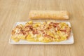 French fries with bacon strips and melted cheese with a rustic loaf of bread Royalty Free Stock Photo