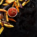 French fries,  baked fries from different types and colors of potatoes sprinkled with herbs and spices with spicy tomato sauce Royalty Free Stock Photo