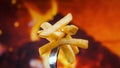 French fries on a fork rotate in front of fire