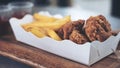 French fries and fried chicken in white paper plate with ketchup and chili sauce in plastic cups