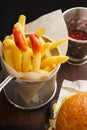 French fries in fry basket and ketchup on a dark wooden board Royalty Free Stock Photo