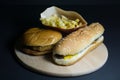 French fries with hamburger and hot dog on wooden tray on black background Royalty Free Stock Photo