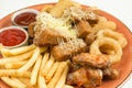 French fries, onion rings, chicken wings, rusks, a snack to beer on a large plate with two sauces on a brown background. Royalty Free Stock Photo