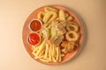 French fries, onion rings, chicken wings, rusks, a snack to beer on a large plate with two sauces on a brown background. Top view. Royalty Free Stock Photo