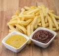 French fries on wooden board with catchup & mustard sauce