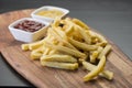 French fries on wooden board with catchup & mustard sauce