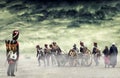 French grenadier watching napoleonic soldiers and women marching and pulling a cannon in plain land, countryside with stormy cloud