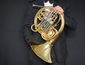 French horn player. Music instrument horn in the hands of hornist. A man in a suit with a musical instrument.