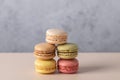 French macarons in pink, yellow, green, beige and brown arranged in geometric stack on beige surface with gray background. Royalty Free Stock Photo