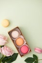 French macaroons. Many variegated sweet macarons in box with bouquet of pink roses on the table Royalty Free Stock Photo