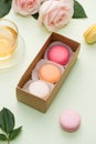 French macaroons. Many variegated sweet macarons in box with bouquet of pink roses on the table Royalty Free Stock Photo