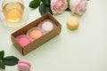 French macaroons. Many variegated sweet macarons in box with bouquet of pink roses on the table Royalty Free Stock Photo