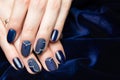 French manicure - beautiful manicured female hands with blue manicure with rhinestones on dark blue background Royalty Free Stock Photo