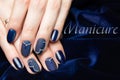 French manicure - beautiful manicured female hands with blue manicure with rhinestones on dark blue background Royalty Free Stock Photo