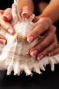 French manicure gel polish. Strong and healthy nails concept. Beautiful female hands on a black background with a cockleshell Royalty Free Stock Photo