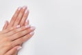 French manicure. Nude nails covered with gel polish on a white background with copy space. Natural manicure with camouflage base.