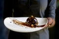 French mini mousse pastry dessert in chocolate icing on a plate. Dessert in the hands of a waitress. Royalty Free Stock Photo