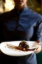 French mini mousse pastry dessert in chocolate icing on a plate. Dessert in the hands of a waitress. Royalty Free Stock Photo